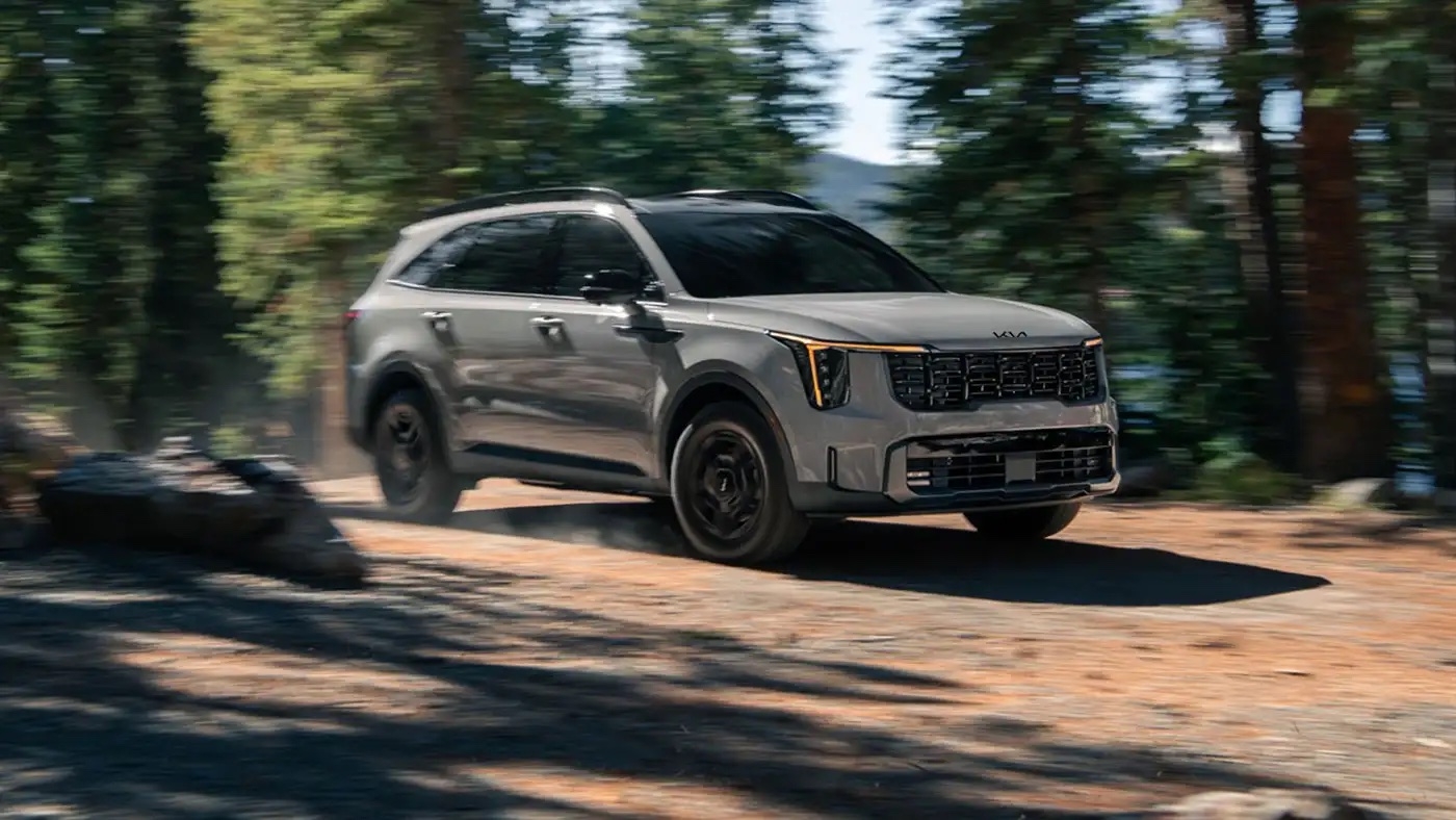 vue latérale avant d'une Kia Sorento sur un sentier en forêt