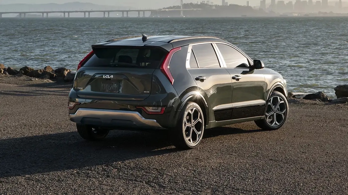 Vue arrière du Kia Niro HEV 2025 stationné au bord de l’eau, mettant en valeur le design du hayon.