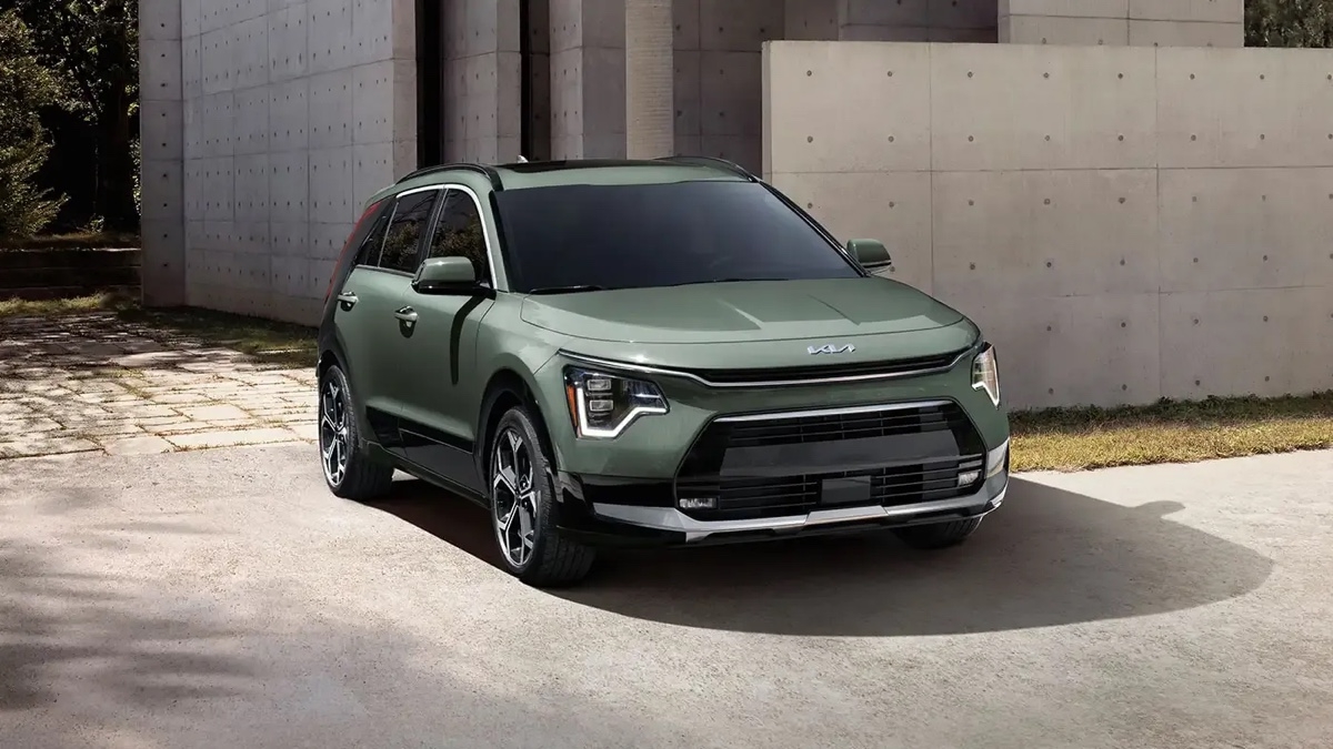 Vue extérieure avant du Kia Niro HEV 2025 stationné devant une maison moderne.